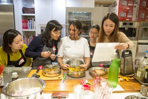 Chef Teena leading a hands-on chef demo with a small group