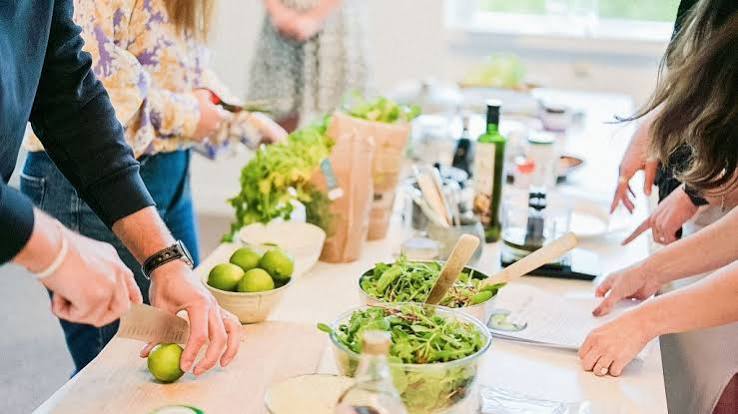 Group hands-on wellness cooking session with fresh greens and produce