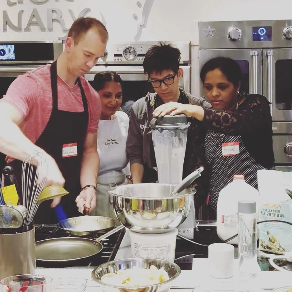 Team working station-to-station on a collaborative menu with Chef Teena