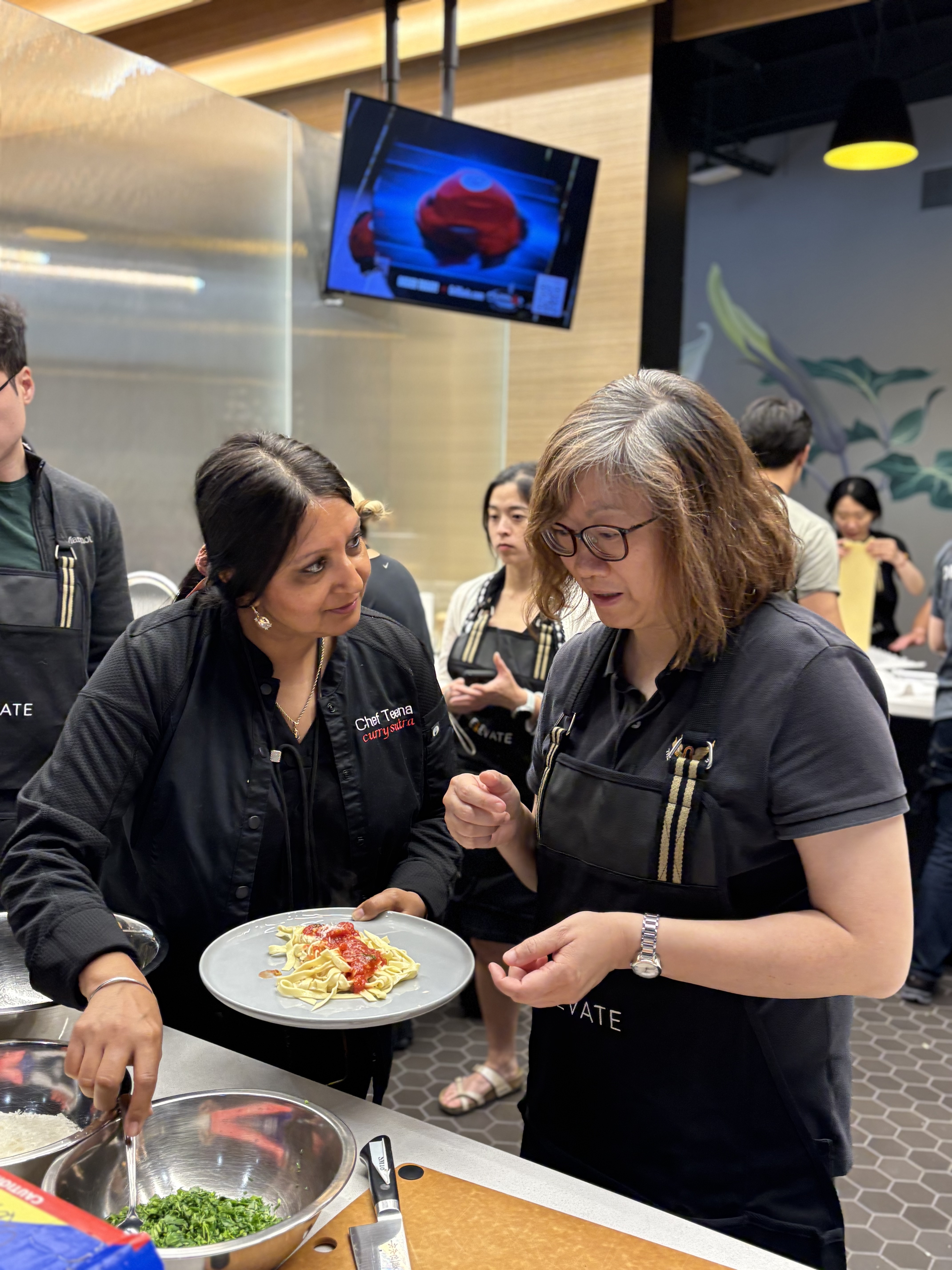 Chef Teena guiding a participant through fresh pasta and sauce plating