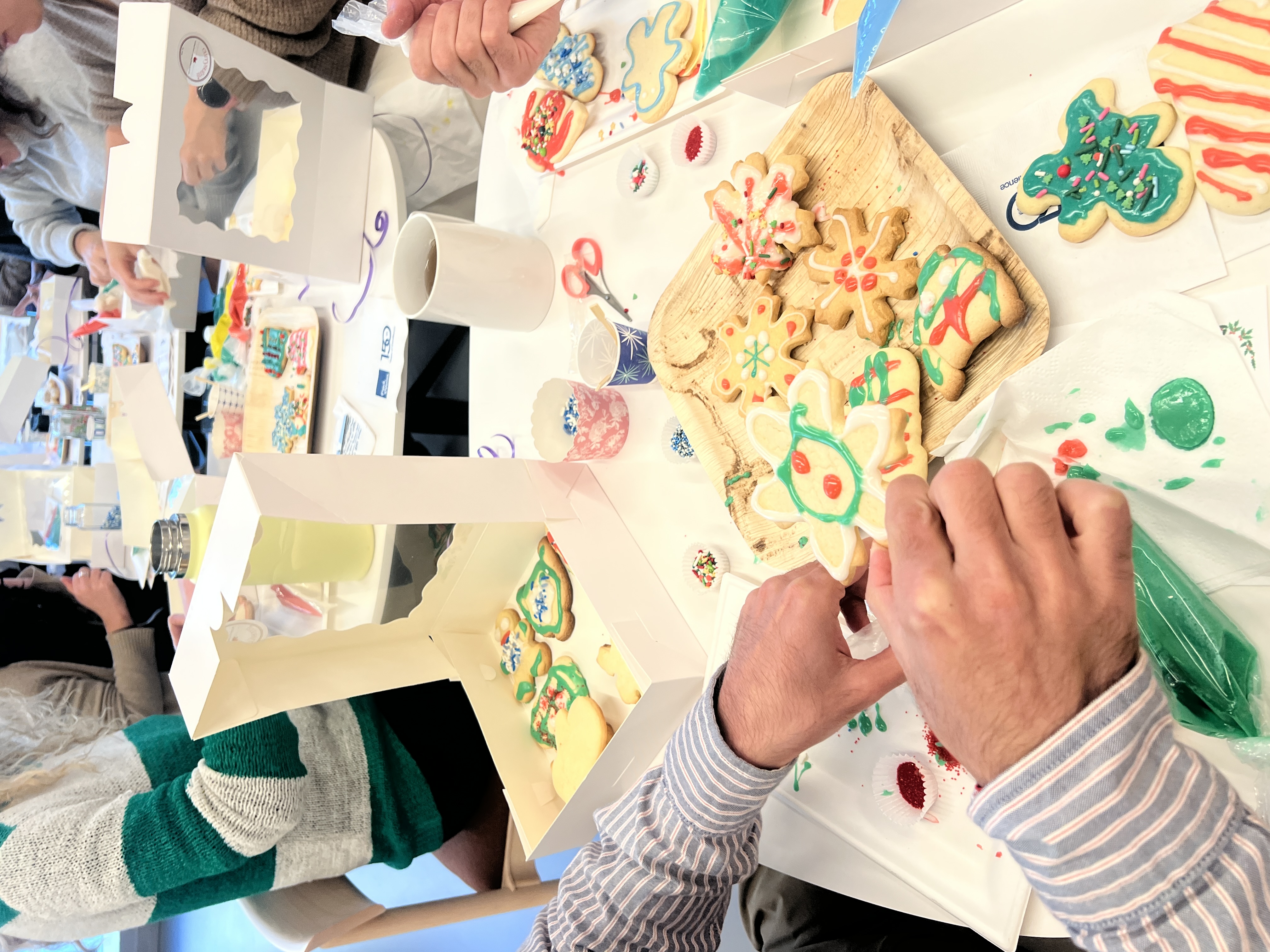 Team decorating holiday sugar cookies together with colorful icing