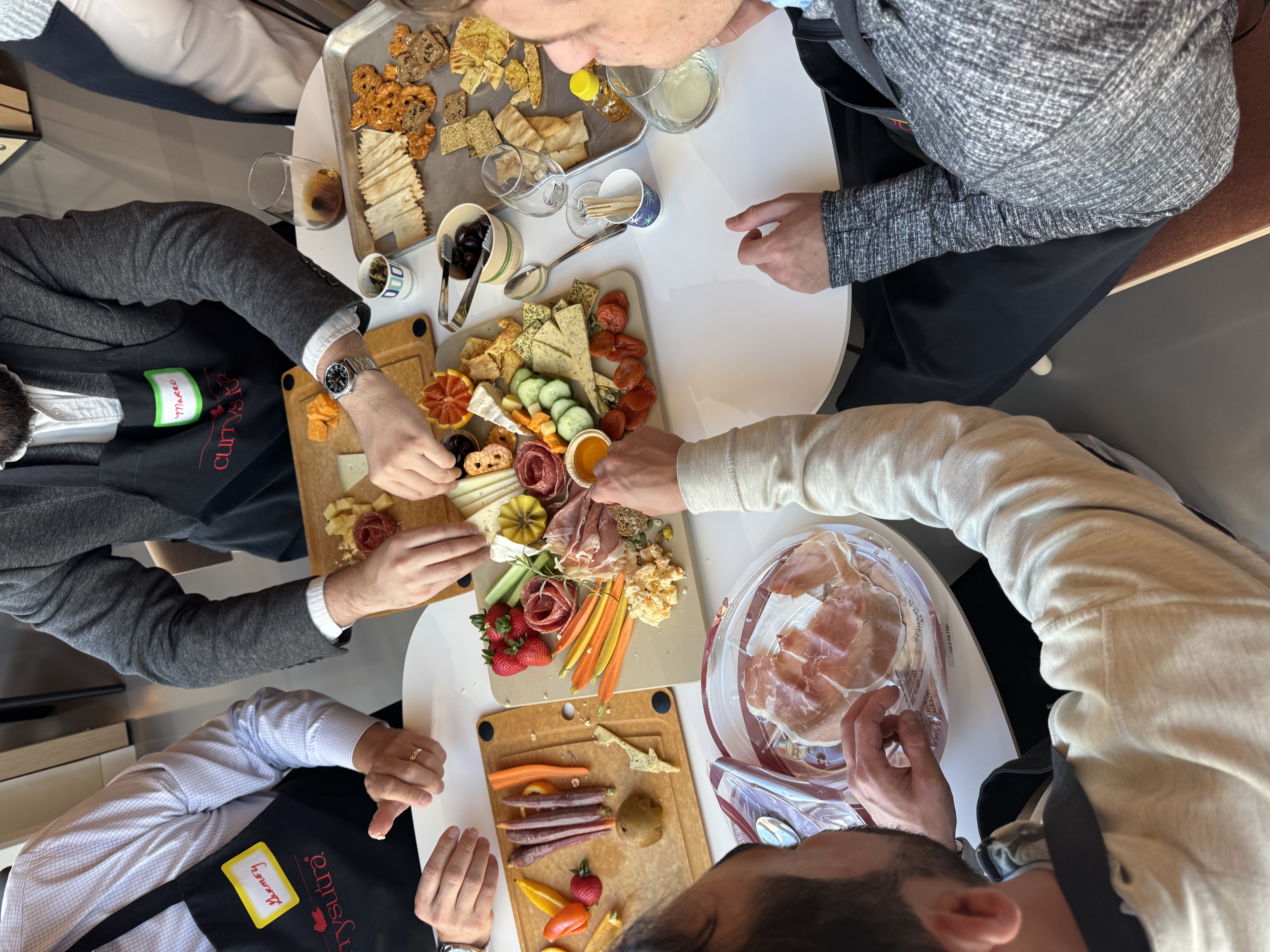 Team building a charcuterie and cheese board together with honey