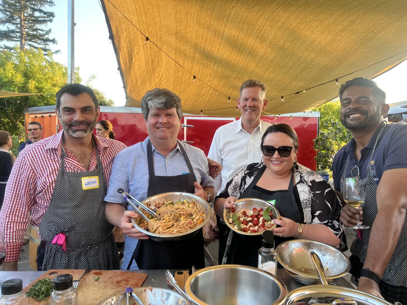 Team members smiling together with dishes they cooked at a team-building session